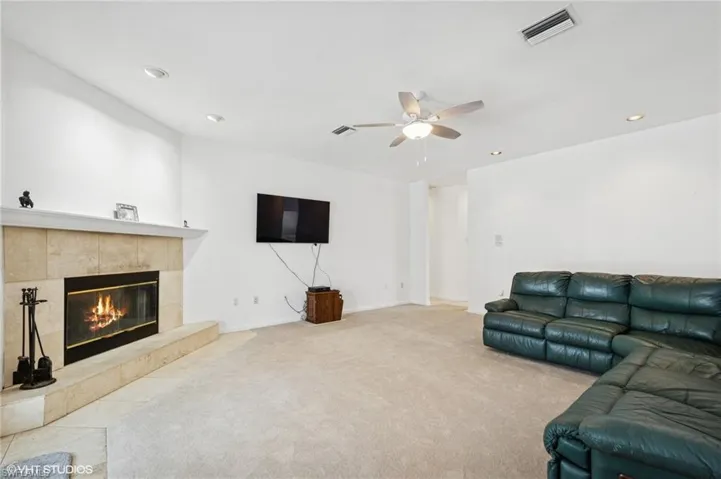 Carpeted living area featuring new ceiling fan, a fireplace and recessed lighting