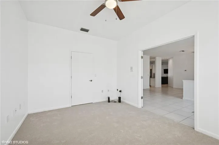 Empty room featuring a ceiling fan, light carpet, visible vents, and baseboards