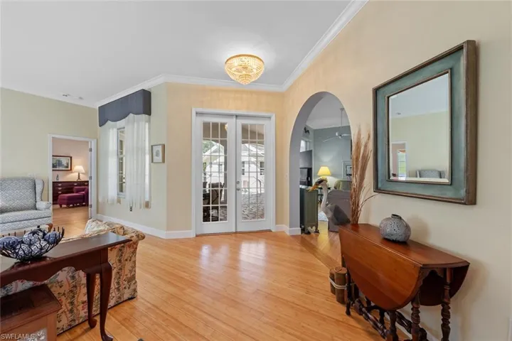 Foyer with light wood finished floors, arched walkways, french doors, and ornamental molding
