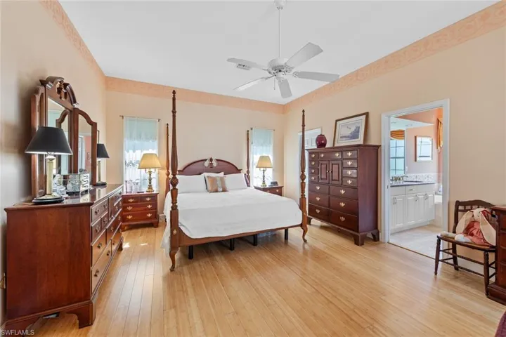 Bedroom with multiple windows, a ceiling fan, light wood finished floors, and connected bathroom