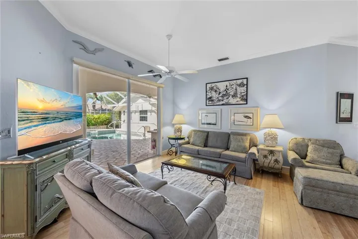 Living room featuring visible vents, crown molding, light wood finished floors, baseboards, and ceiling fan