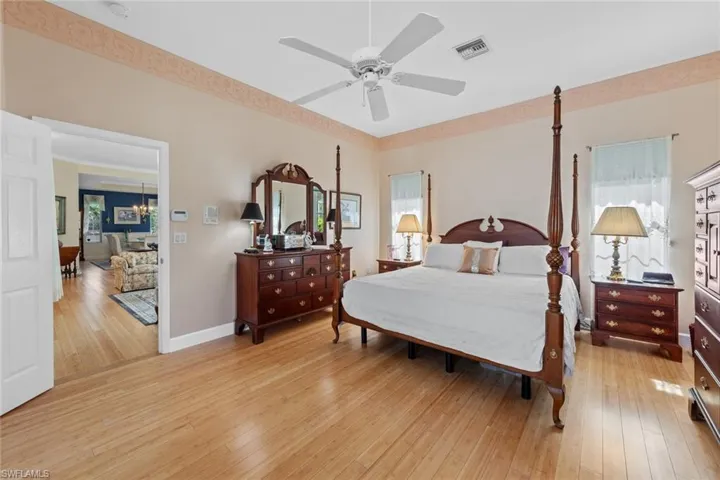 Bedroom with visible vents, light wood-style flooring, baseboards, and multiple windows
