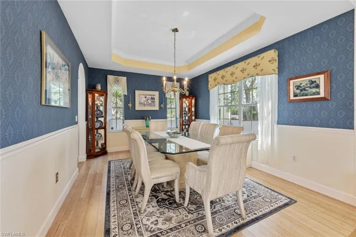Dining area with wallpapered walls, a chandelier, and wainscoting