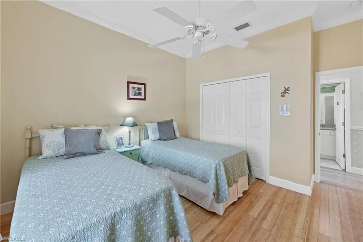 Bedroom featuring light wood-type flooring, visible vents, a closet, crown molding, and baseboards