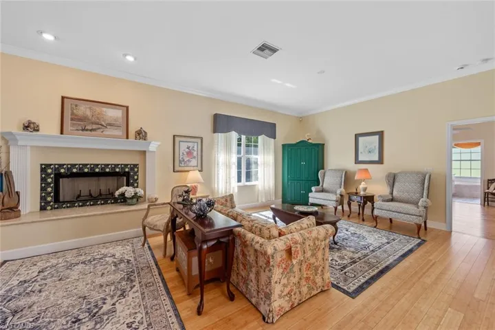 Living room with visible vents, ornamental molding, wood finished floors, a fireplace, and baseboards