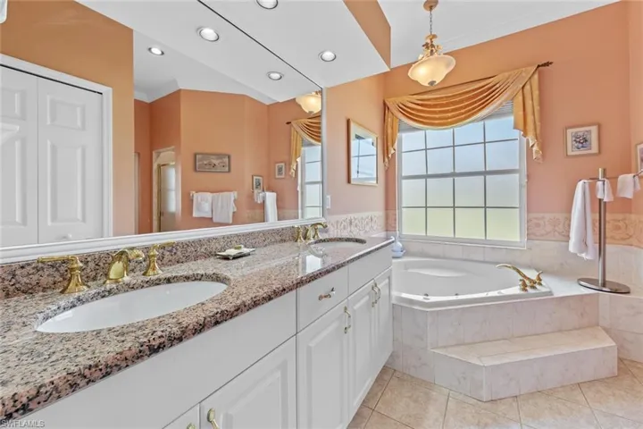 Bathroom featuring tile patterned floors, a jetted tub, double vanity, and a sink