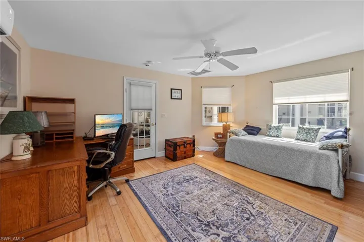 Bedroom with visible vents, baseboards, ceiling fan, an AC wall unit, and light wood-style floors