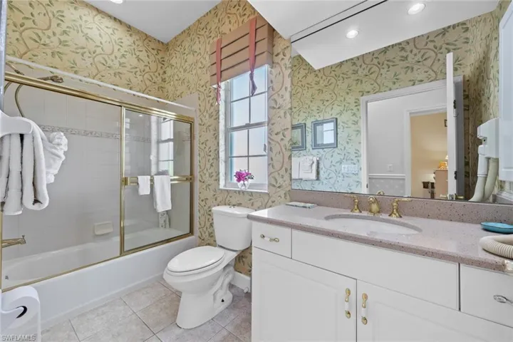 Bathroom featuring wallpapered walls, toilet, vanity, and tile patterned flooring