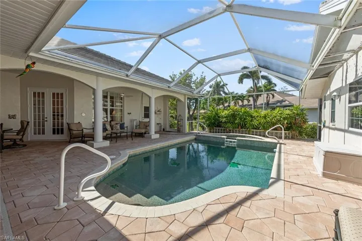 View of swimming pool with french doors, a pool with connected hot tub, and a patio