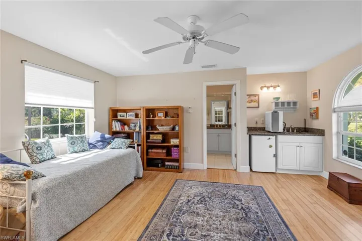Bedroom featuring a ceiling fan, visible vents, baseboards, ensuite bath, and light wood-style floors