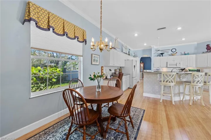 Dining area featuring crown molding, baseboards, light wood-type flooring, and arched walkways