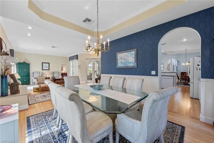 Dining area with visible vents, a notable chandelier, ornamental molding, light wood-style floors, and wallpapered walls