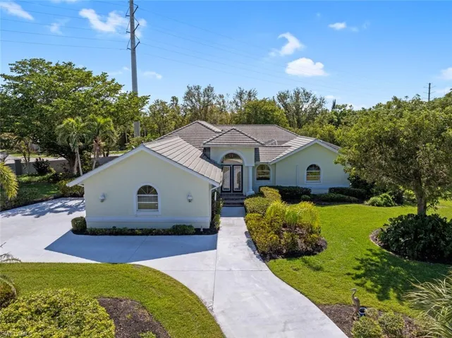 View of front facade featuring stucco siding, concrete driveway, a tile roof, and a front yard