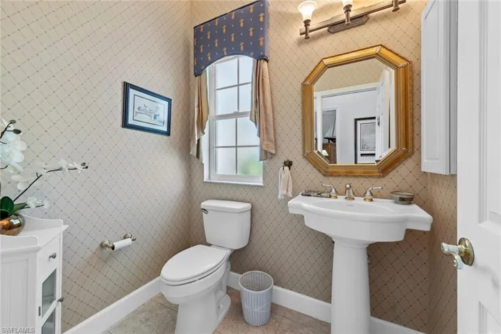 Half bath with tile patterned floors, wallpapered walls, toilet, and baseboards