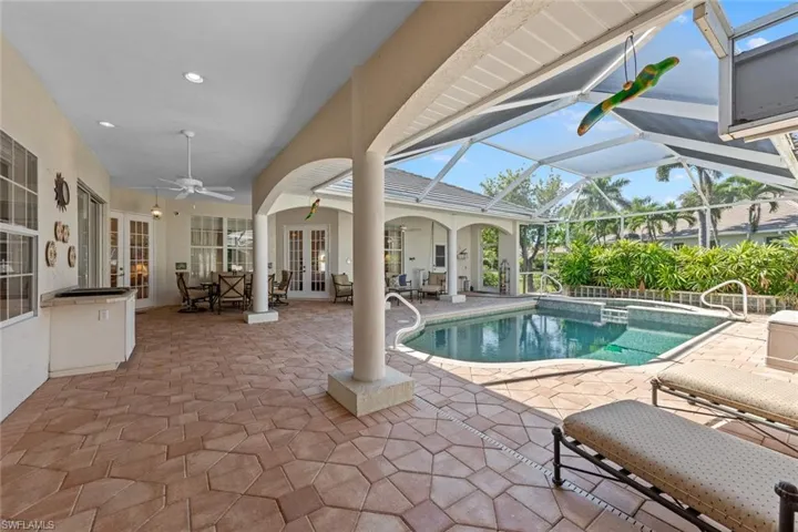 View of swimming pool featuring a patio, a ceiling fan, a pool with connected hot tub, french doors, and a lanai