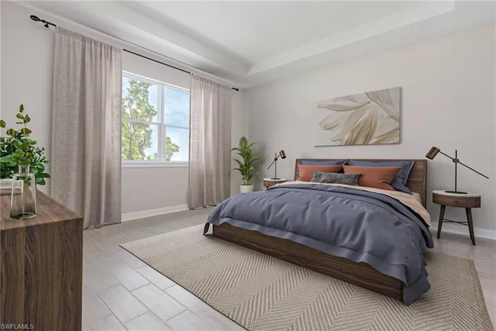 Bedroom with a tray ceiling and light hardwood / wood-style flooring