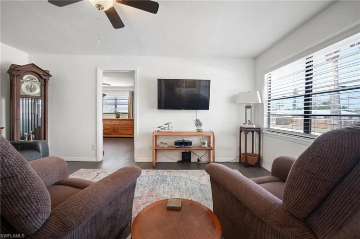 Living area with plenty of natural light, wood finished floors, and ceiling fan