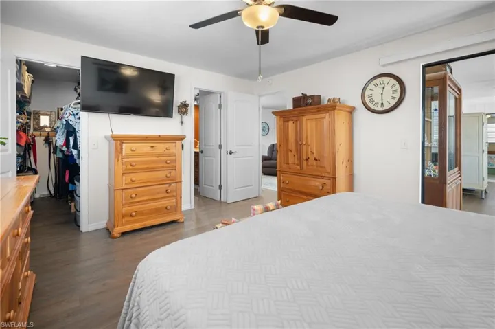 Bedroom with wood finished floors, a walk in closet, and ceiling fan