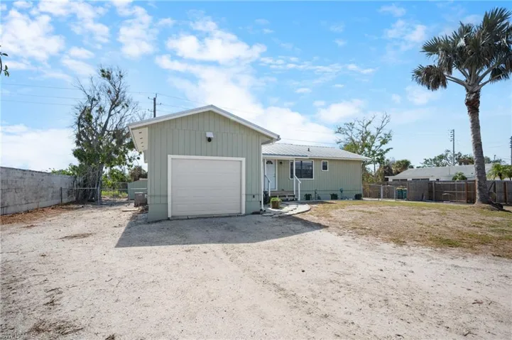 View of front of property with dirt driveway and a garage