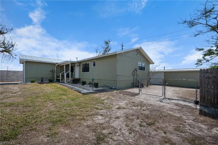 Rear view of house featuring a gate, a metal roof, and a patio