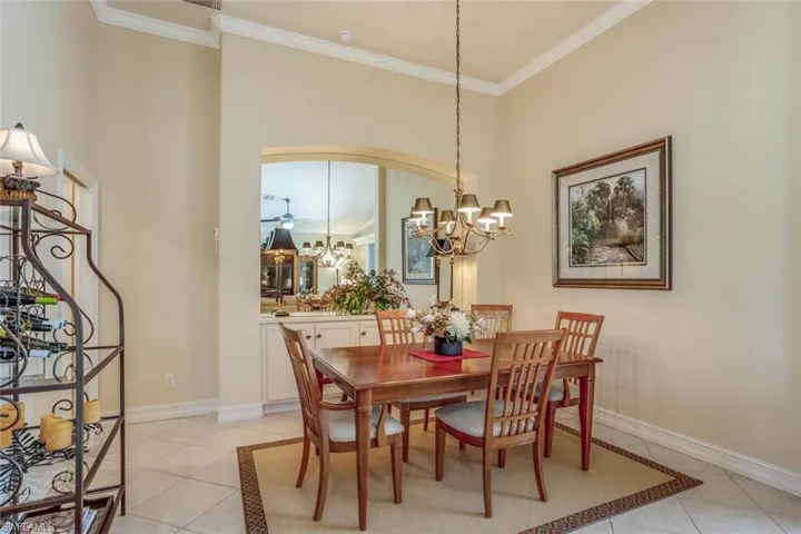 Dining room featuring ornamental built in with cabinetry, chandelier, light tile patterned floors, and a high ceiling