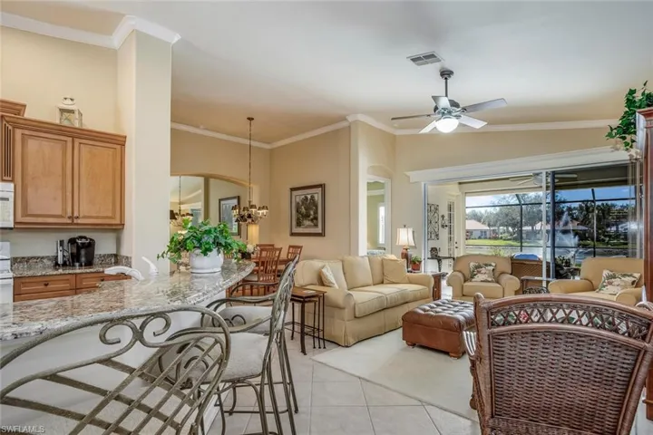 Living area featuring crown molding, light tile patterned floors, a ceiling fan, and vaulted ceiling