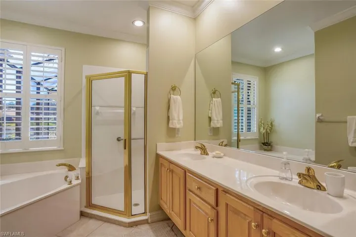 Primary bathroom features a garden bath, a stall shower, double vanity, recessed lighting, water closet, spacious walk in closet and crown molding