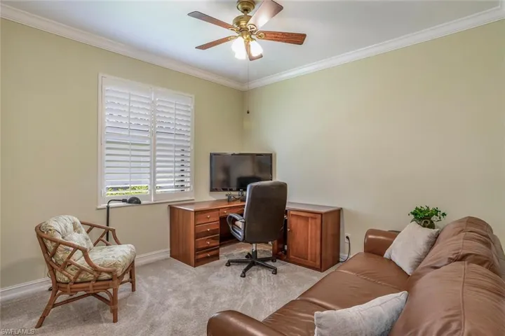 Third bedroom is being used as an office space with ornamental molding, light carpet, closet and a ceiling fan