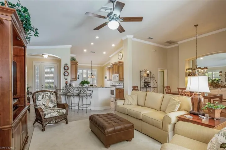 Living room with vaulted ceiling, a ceiling fan, open floorplan, and crown molding