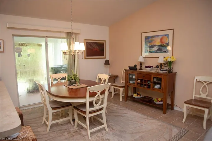 Tiled dining area featuring lofted ceiling and an inviting chandelier