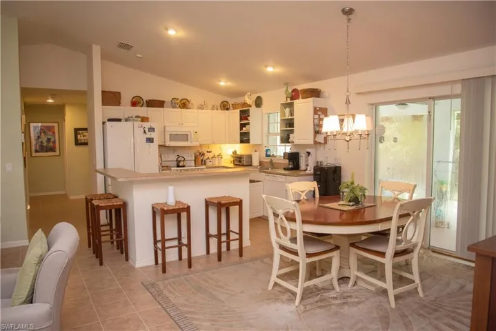 Dining room with light tile patterned flooring, sink, lofted ceiling, and a chandelier