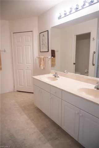 Bathroom with double sink vanity, toilet, and tile patterned flooring