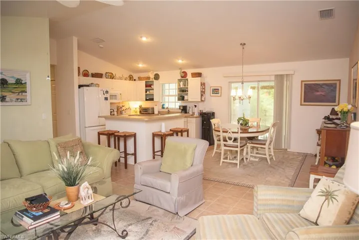 Living room with light tile patterned floors, lofted ceiling, and plenty of natural light