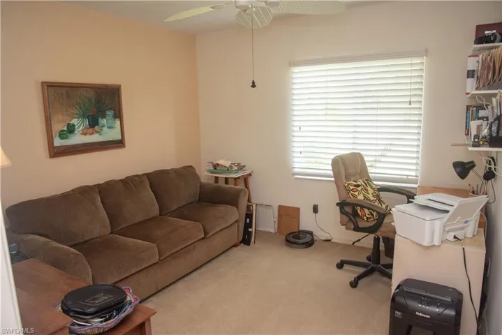 Carpeted home office featuring ceiling fan