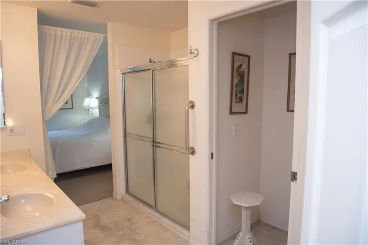 Bathroom featuring dual bowl vanity, walk in shower, and tile patterned flooring