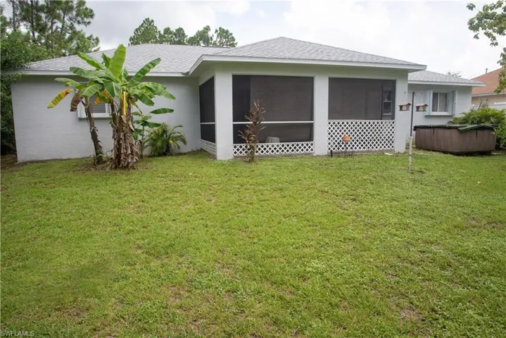 Back of property with a lawn and a sunroom