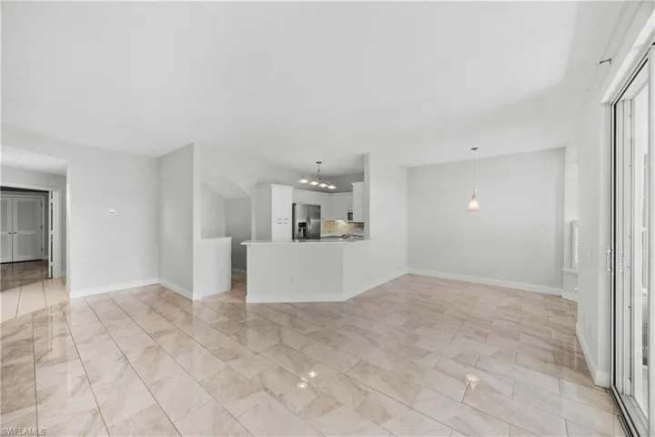 Unfurnished living room with baseboards and a chandelier