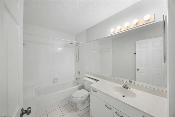 Bathroom featuring vanity, tub / shower combination, light tile patterned floors, and a textured ceiling