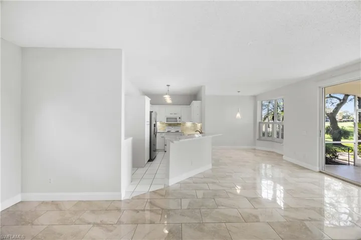 Kitchen featuring decorative light fixtures, white cabinets, open floor plan, white microwave, and stainless steel fridge