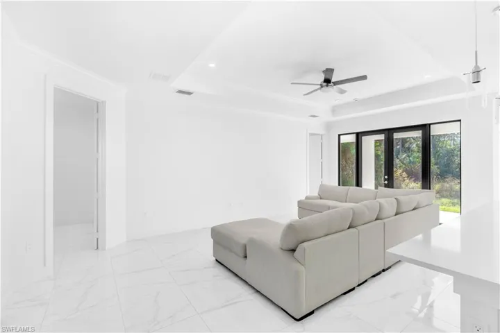 Living area with crown molding, light marble finish flooring, recessed lighting, and a raised ceiling