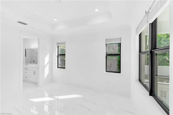Spare room featuring light marble finish flooring, crown molding, a raised ceiling, and recessed lighting