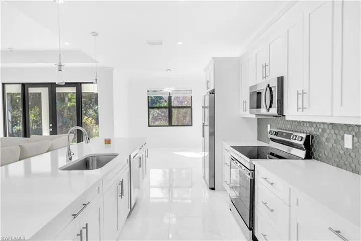 Kitchen featuring stainless steel appliances, white cabinetry, decorative light fixtures, tasteful backsplash, and recessed lighting
