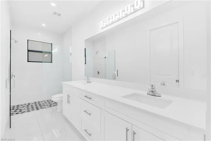 Full bathroom with a stall shower, double vanity, and recessed lighting