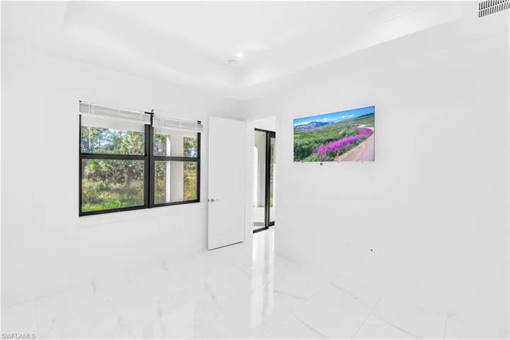 Unfurnished room featuring a raised ceiling, marble look tiles, and crown molding