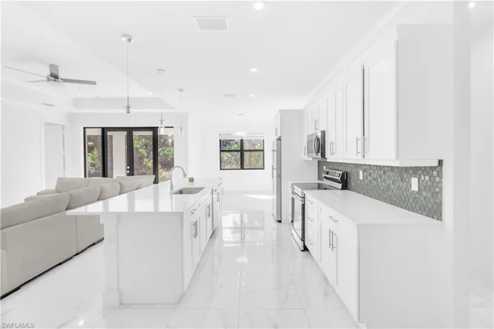 Kitchen with open floor plan, appliances with stainless steel finishes, hanging light fixtures, white cabinetry, and recessed lighting
