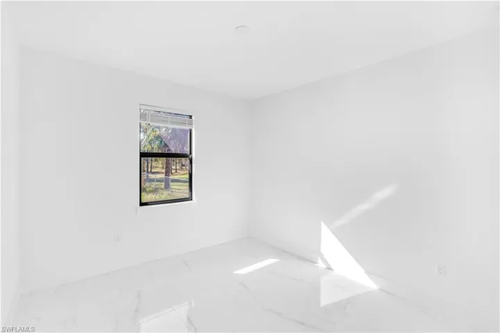 Unfurnished room featuring marble finish flooring and baseboards