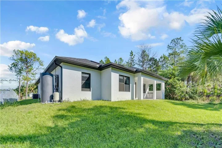 Back of house featuring stucco siding, a patio area, and a yard