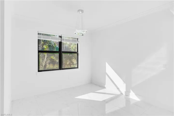 Empty room featuring light marble finish floors and crown molding