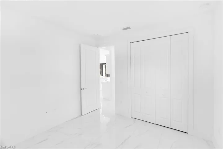 Unfurnished bedroom with light marble finish floors and a closet