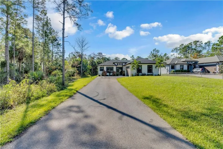 View of front of property with driveway and a front lawn